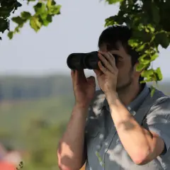 Mężczyzna przez lornetkę obserwuje krajobraz. Czy to co widzi to tylko zwykła **aberracja co to** za zjawisko?