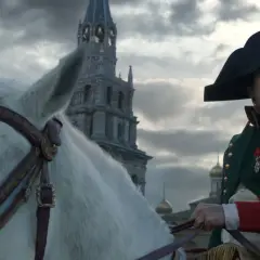 Buńczuczny Napoleon na białym koniu, w tle moskiewskie cerkwie. Jego spojrzenie sugeruje determinację i nieustępliwość.