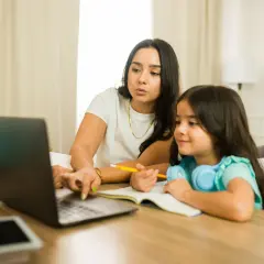 Kobieta z córką uczą się online. Dziecko słucha, a mama tłumaczy, co to są głoski.