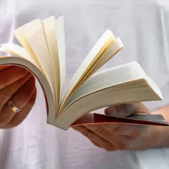 Dłonie trzymają otwartą książkę, przerzucając strony. Czytanie to wewnętrzna psychomachia, co to znaczy?