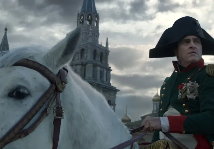 Buńczuczny Napoleon na białym koniu, w tle moskiewskie cerkwie. Jego spojrzenie sugeruje determinację i nieustępliwość.