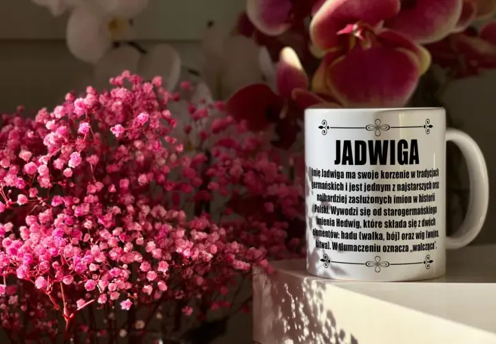 Biały kubek z napisem "Jadwiga" i opisem znaczenia imienia, na tle różowych kwiatów i storczyków.