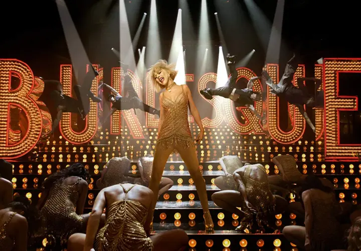 Scena z filmu "Burleska". Wokalistka w złotej sukience na scenie, otoczona tancerzami.