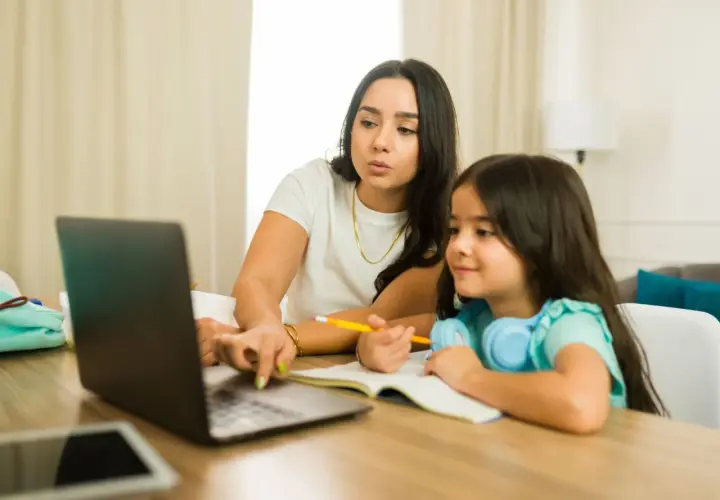 Kobieta z córką uczą się online. Dziecko słucha, a mama tłumaczy, co to są głoski.