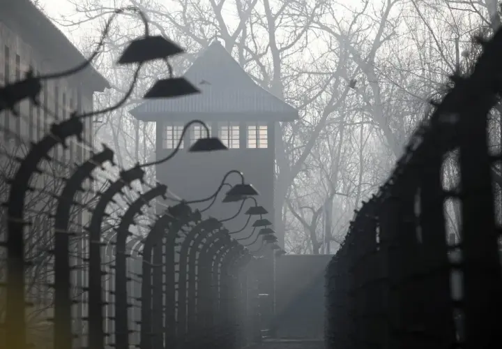 Mglisty poranek w Auschwitz. Strażnicza wieża i druty kolczaste przypominają o mrocznych wydarzeniach. U nas w Auschwitzu streszczenie historii.