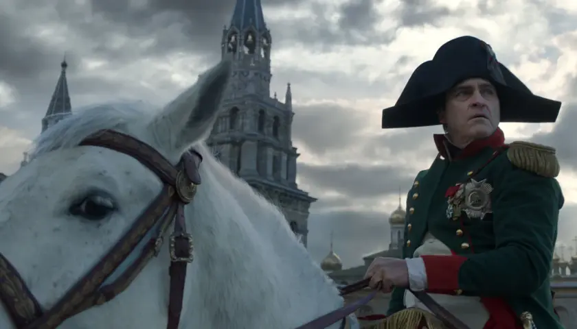 Buńczuczny Napoleon na białym koniu, w tle moskiewskie cerkwie. Jego spojrzenie sugeruje determinację i nieustępliwość.