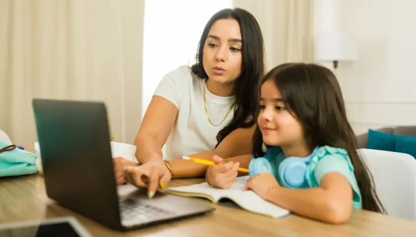 Kobieta z córką uczą się online. Dziecko słucha, a mama tłumaczy, co to są głoski.