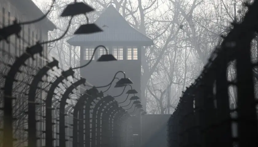 Mglisty poranek w Auschwitz. Strażnicza wieża i druty kolczaste przypominają o mrocznych wydarzeniach. U nas w Auschwitzu streszczenie historii.