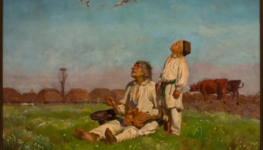 Dwóch mężczyzn w strojach ludowych patrzy na ptaki w locie nad polami i chatami.