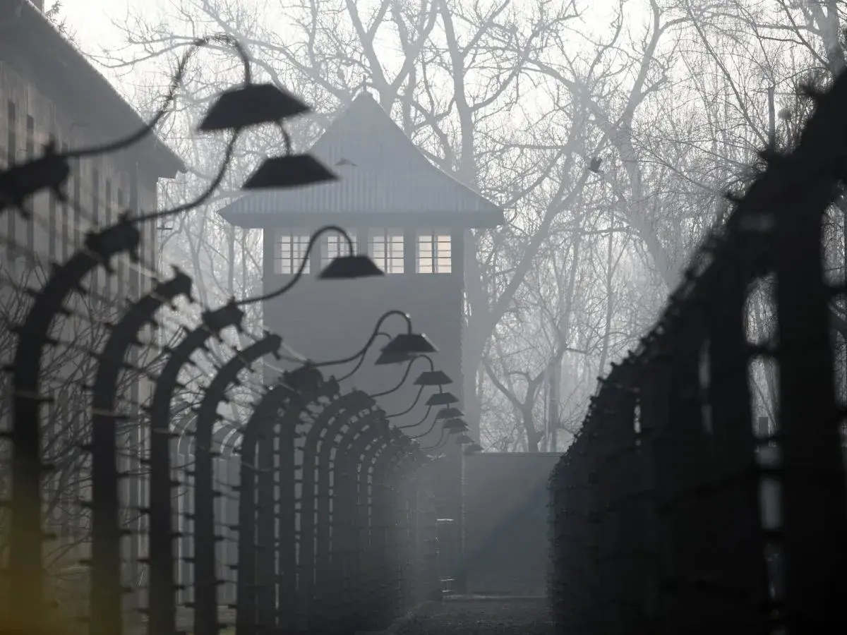 Mglisty poranek w Auschwitz. Strażnicza wieża i druty kolczaste przypominają o mrocznych wydarzeniach. U nas w Auschwitzu streszczenie historii.
