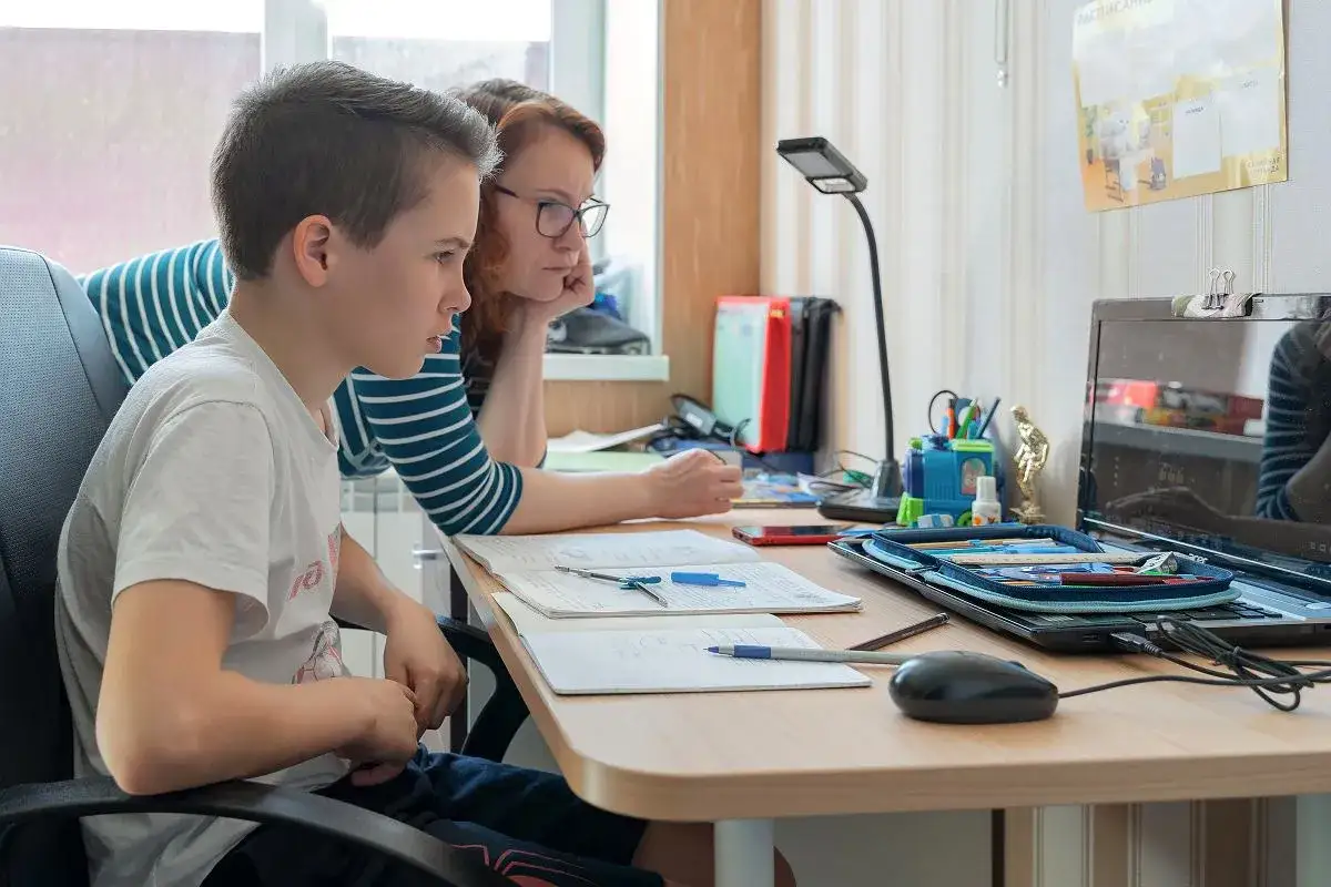 Chłopiec i kobieta uczą się przy biurku. Kto to dyletant? Może ten, kto nie wie, jak pomóc w nauce.