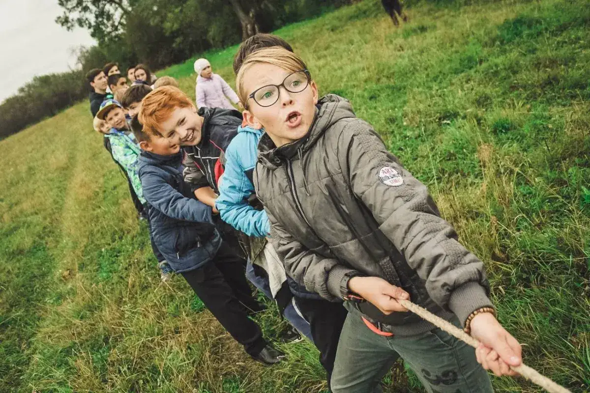 Dzieci wciągają linę, ich usposobienie pełne zaangażowania i radości.