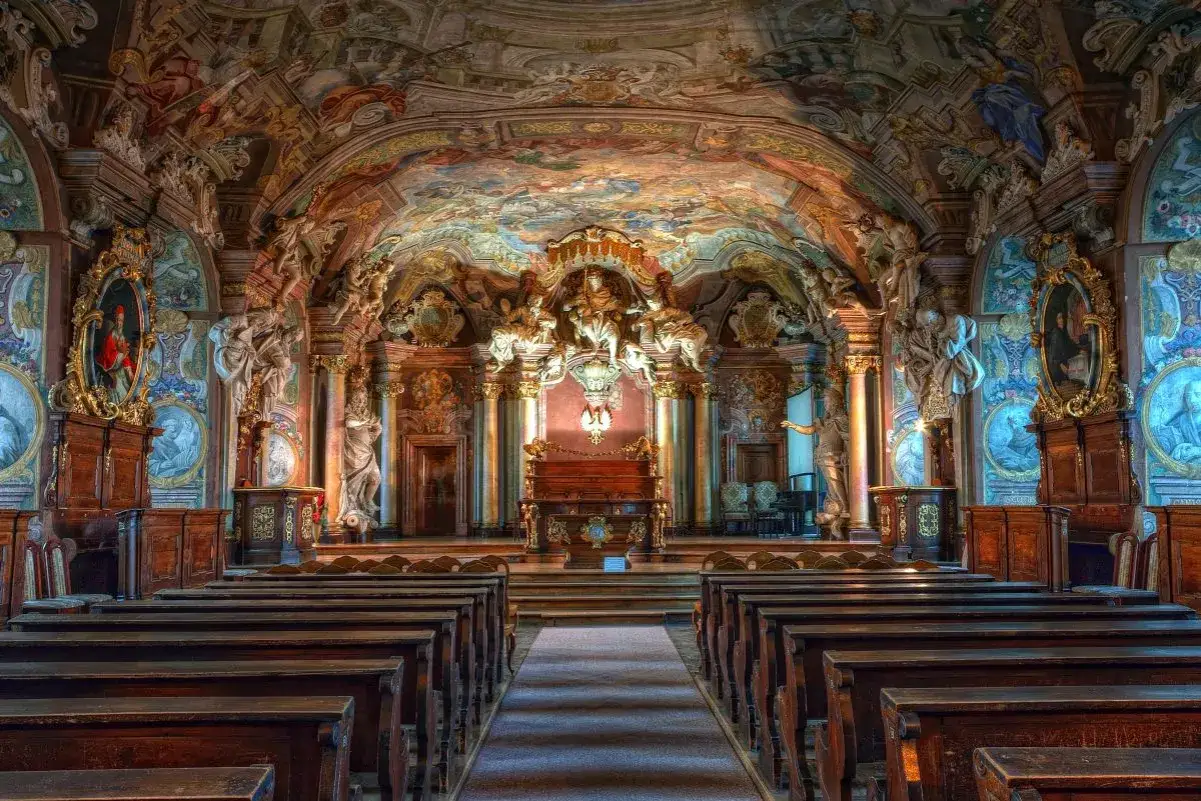 Wnętrze biblioteki z bogatymi zdobieniami, malowidłami na suficie i rzeźbami. To arcydzieło barok w polsce.